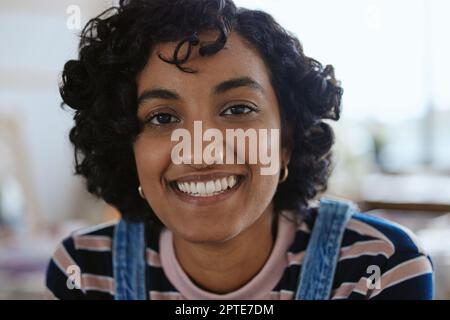 Faccia, ritratto e felice con una giovane donna che si sente spensierata o allegra con un sorriso primo piano. Testa, denti e naso con un attraente, alla moda o. Foto Stock