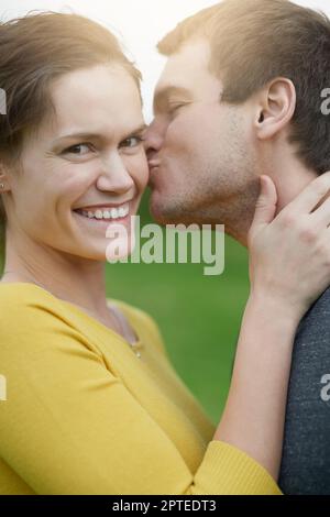 Non riuscì a resistere ad un altro bacio. una donna felice che riceve un bacio dal marito fuori Foto Stock