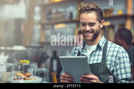 Restare al passo con le tendenze delle piccole e medie imprese con la tecnologia moderna. un giovane uomo che utilizza un tablet digitale nel negozio in cui lavora Foto Stock