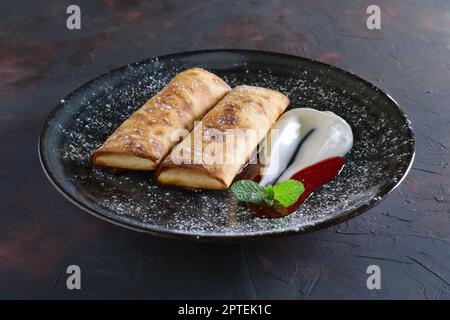 Frittelle dolci ripieni di ricotta e decorate con panna acida e confettura di fragole Foto Stock