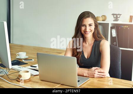 Ive ha lavorato sodo per creare un mondo di opportunità di business. Ritratto di una giovane donna d'affari che lavora su un computer portatile in un ufficio moderno Foto Stock