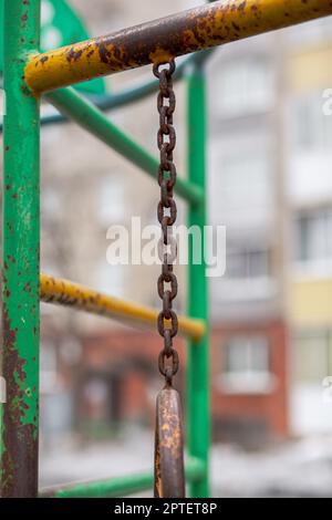 Una catena di ferro con anelli ovali grigi e traslucidi su uno sfondo grigio nel cortile di un edificio a più piani. Un luogo di riposo e di attività per Foto Stock