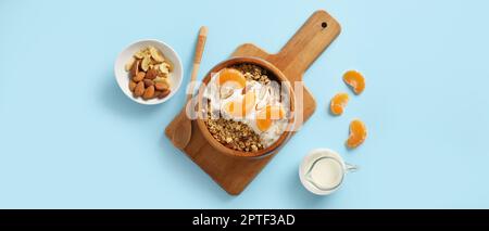 Gustoso granola con yogurt e tangerini in ciotola su sfondo azzurro Foto Stock