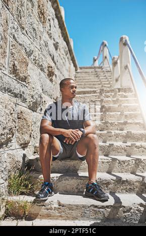 Mantenersi in forma e sentirsi bene. un giovane uomo sportivo seduto fuori Foto Stock