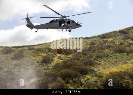 NEGLI STATI UNITI L'elicottero Navy SH-60 Sea Hawk trasporta un secchio di bambi pieno d'acqua in un'area bersaglio durante l'esercizio annuale di estinzione di Cory Iverson Wildland presso il lago Las Pulgas sulla base del corpo dei Marine Camp Pendleton, California, 19 aprile 2023. L'esercitazione antincendio di Cory Iverson Wildland è un evento annuale che si concentra sulla cooperazione interagenzia tra il Dipartimento della silvicoltura e della protezione antincendio della California, il Dipartimento dello sceriffo della contea di San Diego e il Dipartimento della Difesa. Durante l'esercizio, ogni entità lavora insieme per creare un team efficace, efficiente e ben addestrato per rispondere Foto Stock