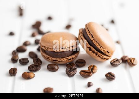 Dolce al macaron. Macaron e chicchi di caffè sul tavolo da cucina. Foto Stock