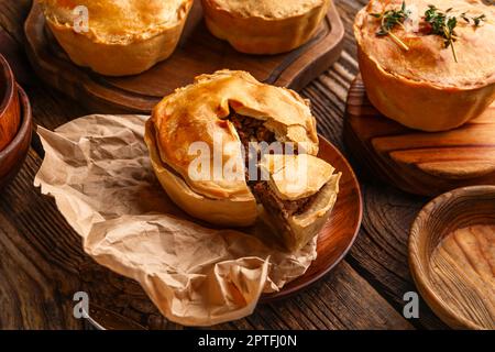 Piatto con gustose torte di carne su sfondo di legno Foto Stock