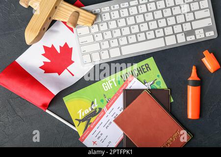 Bandiera canadese con aeroplano di legno, biglietto, passaporti e tastiera per computer su sfondo scuro Foto Stock