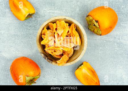 Frutta secca al persimmon con persimmon fresco sul tavolo. Foto Stock