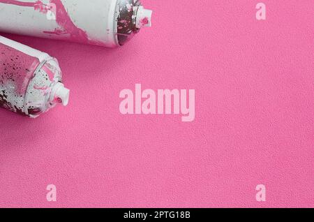 Alcuni usato rosa aerosol bombolette spray con gocce di vernice giace su una coperta di soffice e peloso luce rosa in tessuto di pile. Classic Design femmina colore. Graffiti Foto Stock