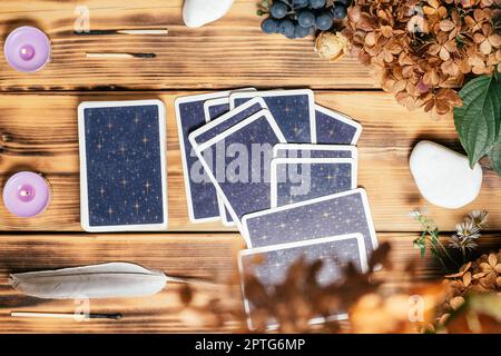 Le carte Tarot si stendono a faccia in giù su una superficie di legno con candele, pietre, piante autunnali e accessori. Vista dall'alto. Minsk, Bielorussia, 11.10.2021 Foto Stock