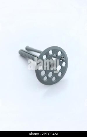 Grigio di un grano di plastica (fissaggio) per isolamento termico con round ombrello caps giace su di una schiuma di colore grigio piastra di polistirene Foto Stock