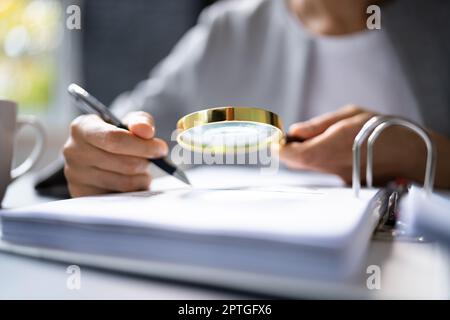 Revisore che utilizza la lente di ingrandimento per l'audit e l'indagine sulle frodi Foto Stock