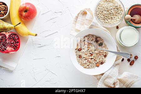 Una ciotola di granola secca e muesli servita con frutta fresca, noci e miele. Piatto di farina d'avena. Cibo sano, dieta. Vista dall'alto. Foto Stock