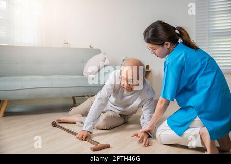 L'uomo anziano disabile paziente con bastone calare a terra e assistente di cura a casa di cura, anziano asiatico cadere sul pavimento sdraiato Foto Stock