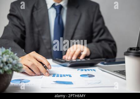Uomo d'affari mano che punta carta grafico rapporto di analisi statistica e grafico finanziario documento con computer portatile a Office.Business investimento ma Foto Stock