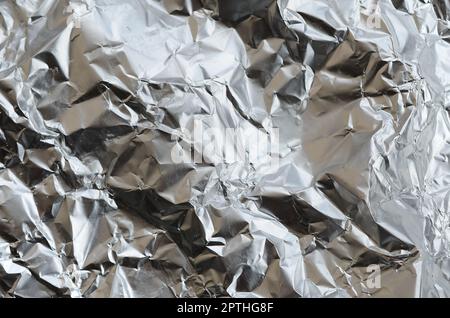 Sottile foglio stropicciato di alluminio stagnato argento sfondo con superficie lucida stropicciata per la texture Foto Stock