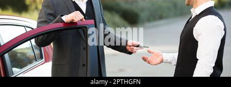 Servizio di parcheggio con parcheggiatore. In piedi vicino alla porta che dà la chiave Foto Stock