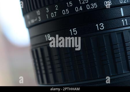 Frammento di un obiettivo grandangolare con zoom per una moderna fotocamera reflex. La serie di valori della distanza è indicata da numeri bianchi sul corpo nero Foto Stock