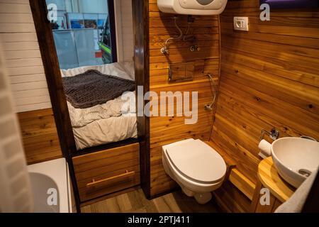 Interno bagno camper con wc, lavabo e pareti in legno. Foto Stock