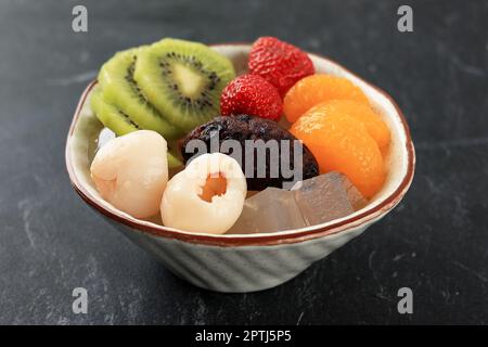 Anmitsu Dessert dolce giapponese con gelatina di Cantina di Agar, frutta mista e pasta di fagioli rossi, primo piano sulla tavola nera Foto Stock