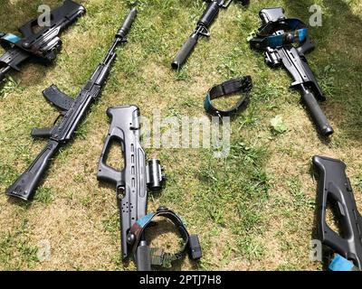 Mitragliatrici militari in ferro nero, armi per soldati con silenziatori giacciono sullo sfondo dell'erba verde. Foto Stock