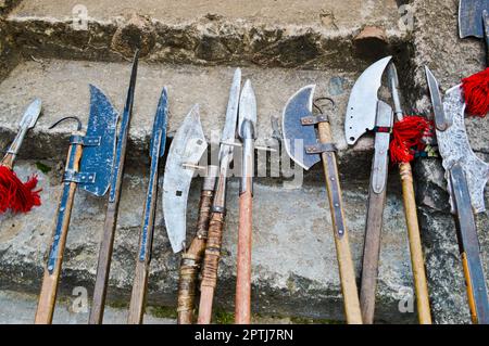 Le vecchie armi fredde medievali, assi, olibardi, coltelli, spade con manici in legno lecca i gradini in pietra del castello. Foto Stock