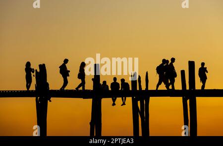 Amarapura, Myanmar - 22 novembre 2016: Persone non identificate camminano sul ponte U Bein al tramonto in Myanmar. Il ponte U Bein è il ponte in teak più lungo del Th Foto Stock