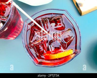 Cocktail rosso con ghiaccio e una fetta di arancia vista dall'alto. Vista dall'alto di un cocktail fresco, gustoso e colorato su un tavolo. Aperitivo italiano Foto Stock