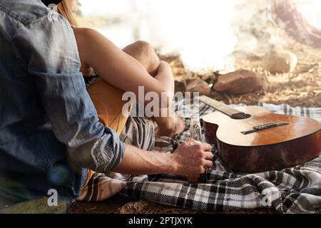 Prendere la vita facile... una coppia stesa su una coperta accanto ad una chitarra Foto Stock