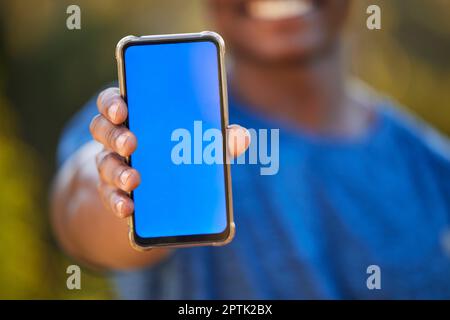 Telefono, mockup e schermo blu in mano di un uomo nero all'aperto per l'esercizio fisico o il monitoraggio del fitness. Marketing, pubblicità e schermo verde con un maschio Foto Stock