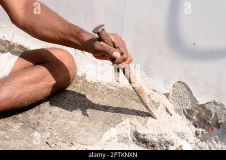Primo piano di una parte del lavoro di costruzione che lavora con martello e scalpello in un cantiere. Foto Stock