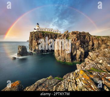 Arcobaleno sul faro di Neist Point sulle verdi scogliere dell'Isola di Skye, Scozia Foto Stock