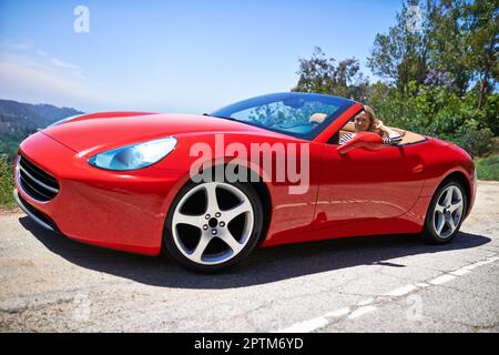 Il mio giro rende tutti gelosi. una giovane donna che guida in un'auto sportiva Foto Stock