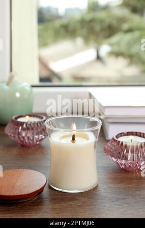 Candele brucianti con libri sul davanzale della finestra di legno Foto Stock