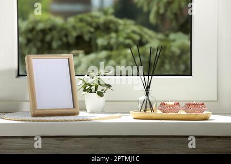 Cornice fotografica vuota con diffusore a lamelle e arredamento per la casa su davanzale bianco Foto Stock