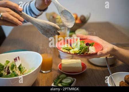 Primo piano dell'uomo che serve insalata alla donna, Monaco, Germania Foto Stock