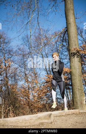 Donna che fa esercizio fisico a ostacolo corso sulla pista di fitness nella foresta Foto Stock