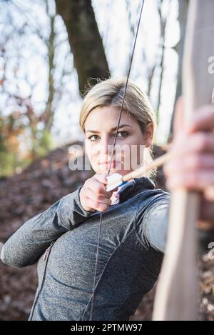 Giovane donna che spara con arco e freccia Foto Stock