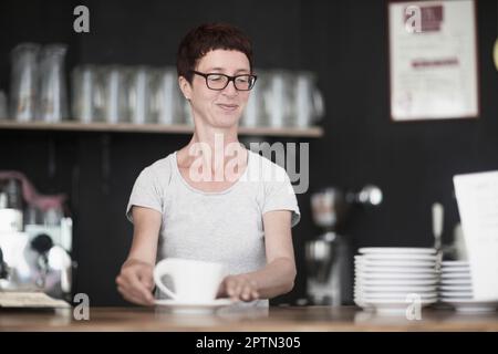 Donna matura che beve caffè nel bar di Friburgo im Breisgau, Baden-Württemberg, Germania Foto Stock