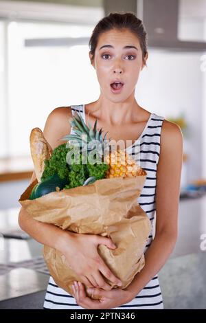 Cibo sano mi fa eccitare. Una donna attraente che tiene un sacchetto dei generi alimentari nella cucina Foto Stock