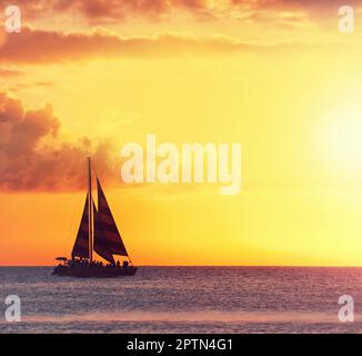 Una foto del tramonto a Waikiki, Honolulu, Hawaii. una barca a vela sull'oceano contro il sole tramontato Foto Stock