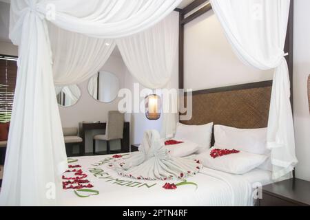 Asciugamani bianchi freschi con fiori sul letto interno Foto stock - Alamy