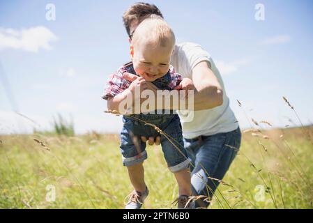 Felice uomo che gioca con suo figlio in campagna, Baviera, Germania Foto Stock