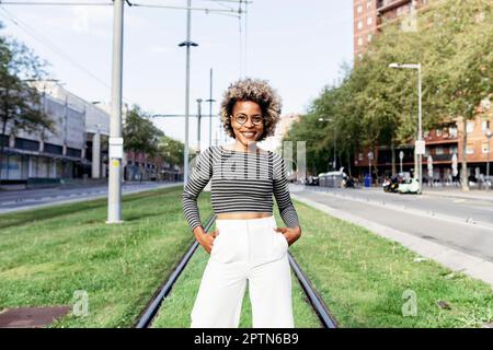 Ritratto di donna afro-americana in posa per strada con pantaloni bianchi Foto Stock