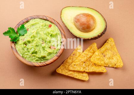 Guacamole ciotola avocado e patatine isolato sul tavolo. Giacitura piatta. Foto Stock
