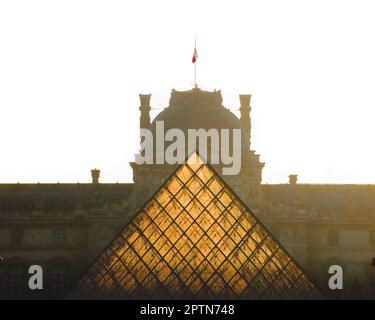 Piramide del museo del Louvre illuminata dai raggi del sole all'alba Foto Stock