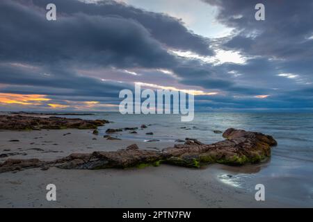 Tramonto spettacolare sulla spiaggia sotto il faro di Covesea Skerries, Foto Stock