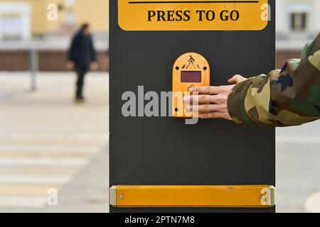 Una mano di un uomo preme un sensore del semaforo per accendere il verde Foto Stock