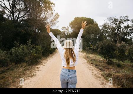 Bella ragazza dai capelli biondi posa in mezzo a un campo di fiori di colza gialli fiorenti Foto Stock